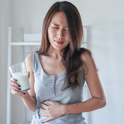 Women holding her stomach likley due to a food allergy or sensitivity.