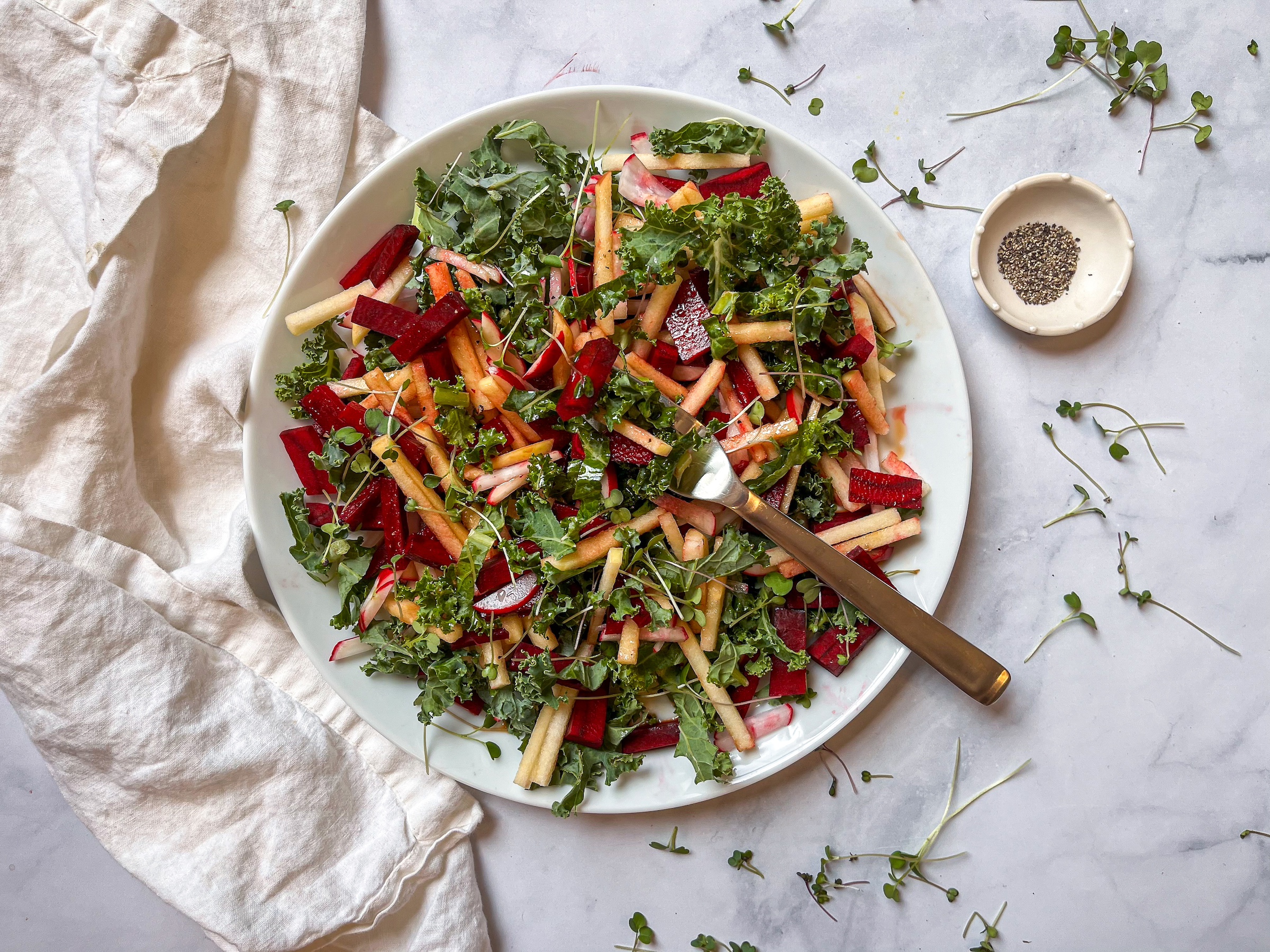 Red root kale salad plated with a side of pepper. 