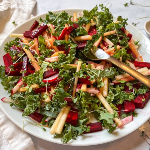 Close-up shot of red root kale salad plated with a fork.