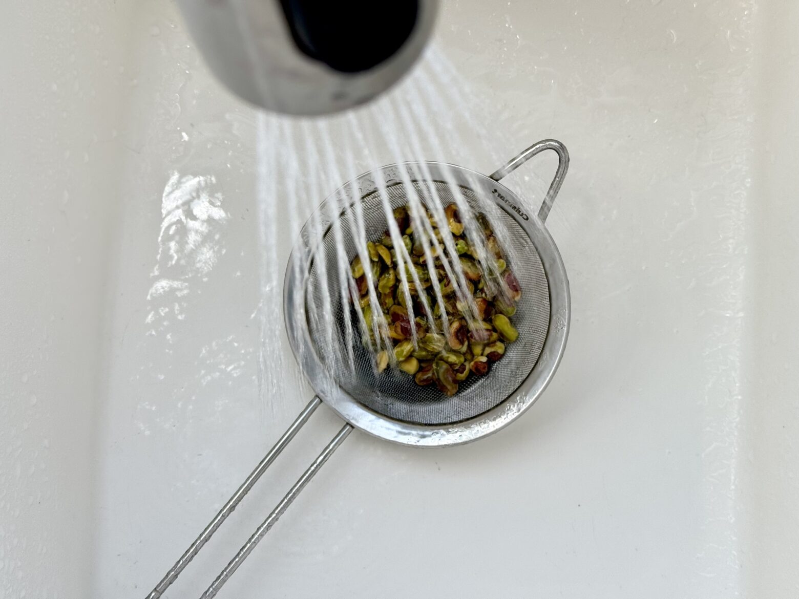 Rinsing pistachios in the sink.