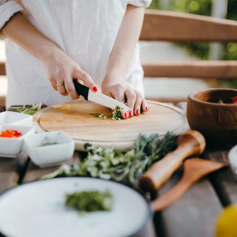 Women outside on a patio, cutting vegetables.