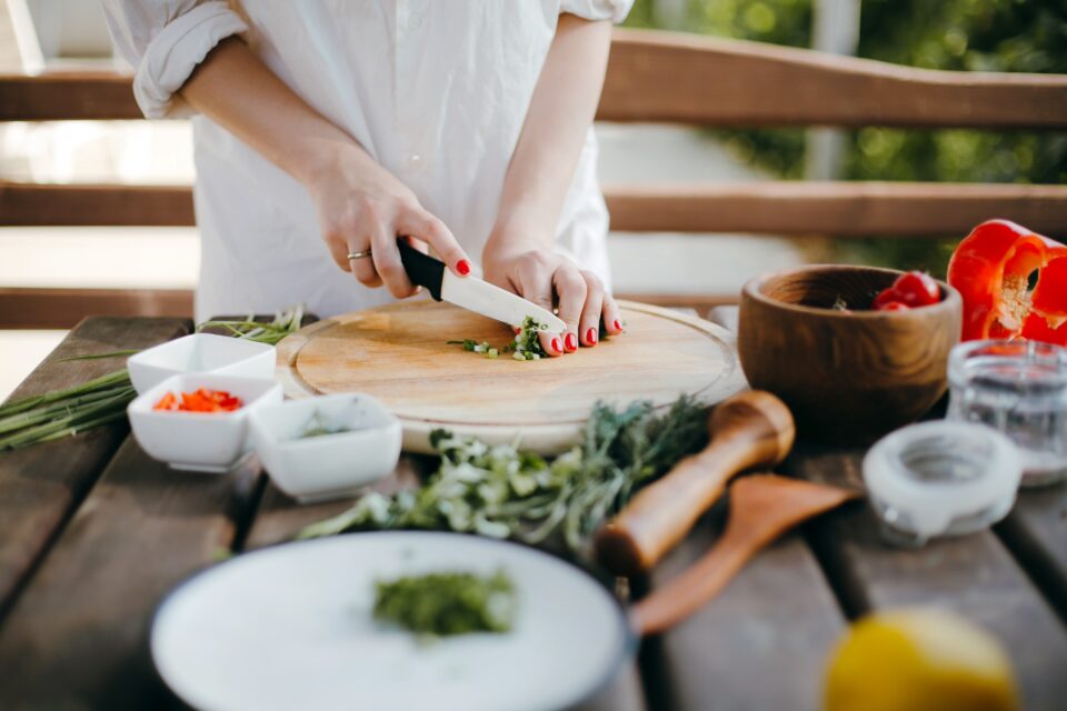 Women outside on a patio, cutting vegetables.
