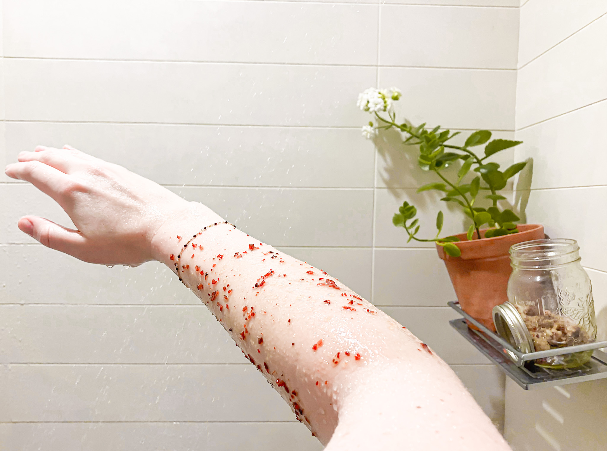 Exfoliating sugar scrub being used in the shower on a arm. 