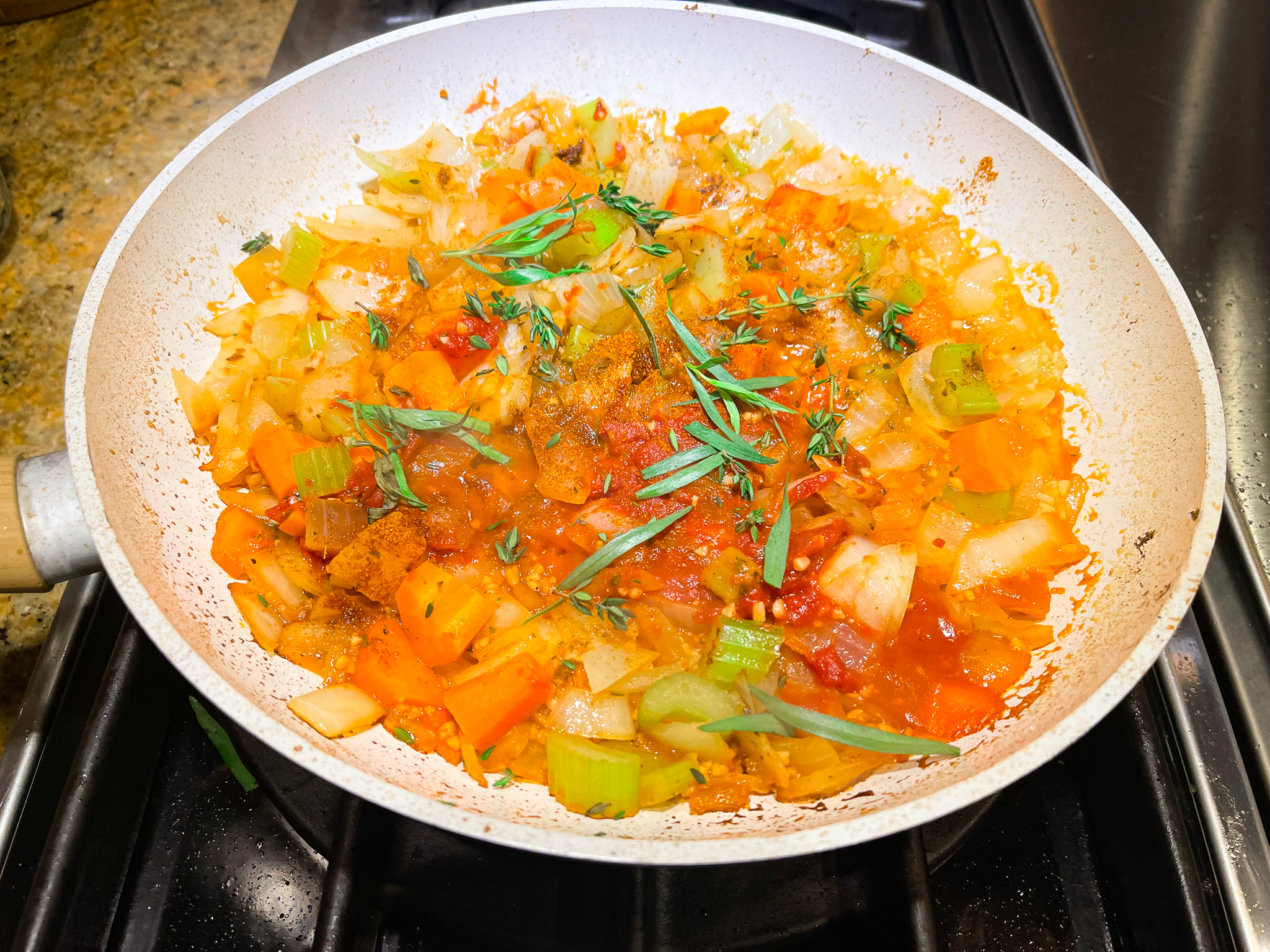 Vegetables and herbs cooking over the stove for lobster bisque.