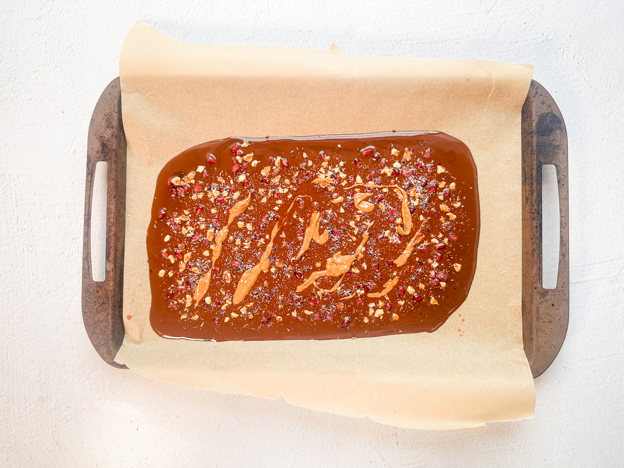 Pomegranate Chocolate bark prep with toppings, melted chocolate, and nut butter. 