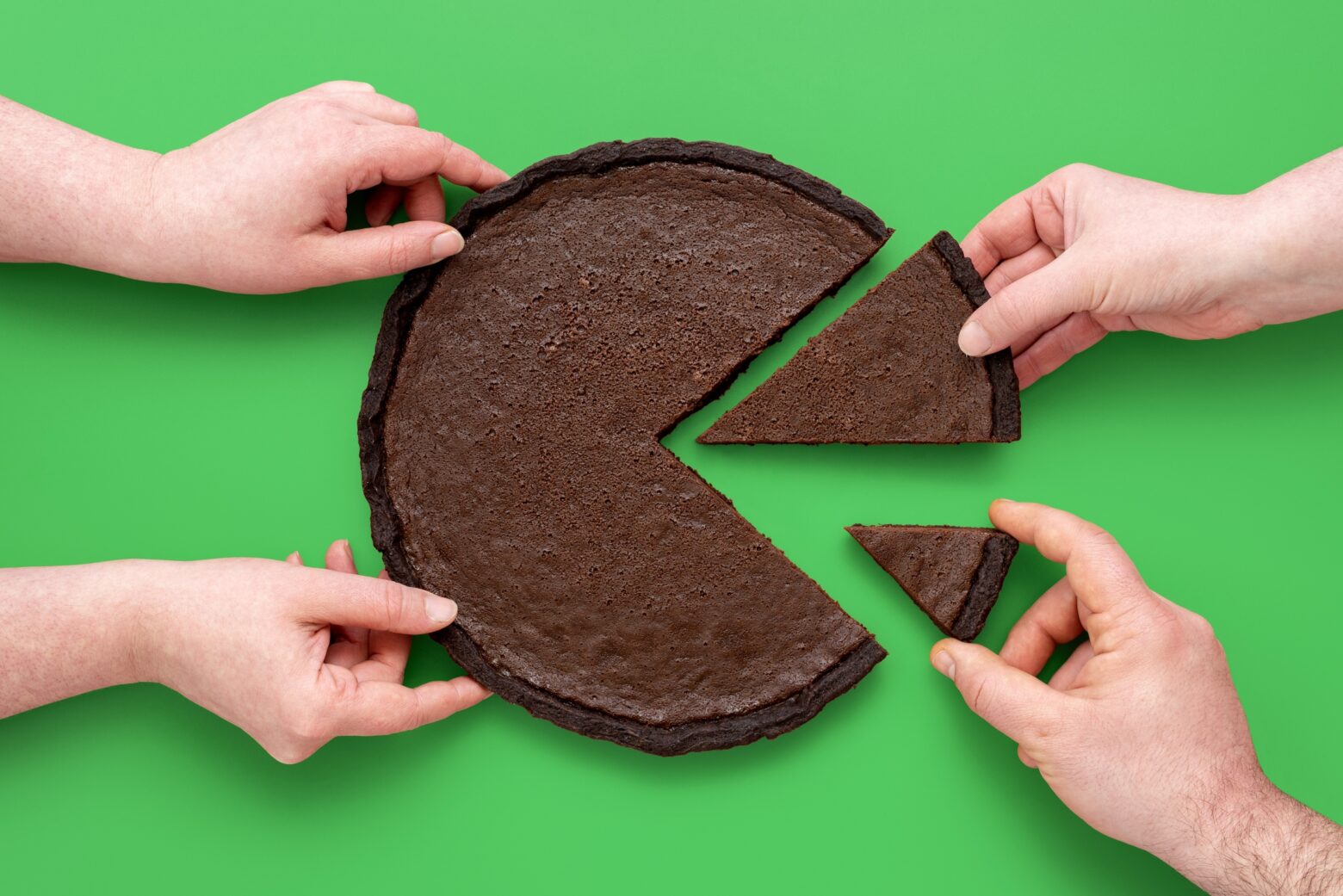 Different hands taking away different portion sizes of a circular brownie