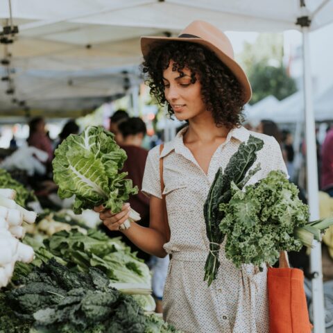 Women shopping at the farmer's market for kale.