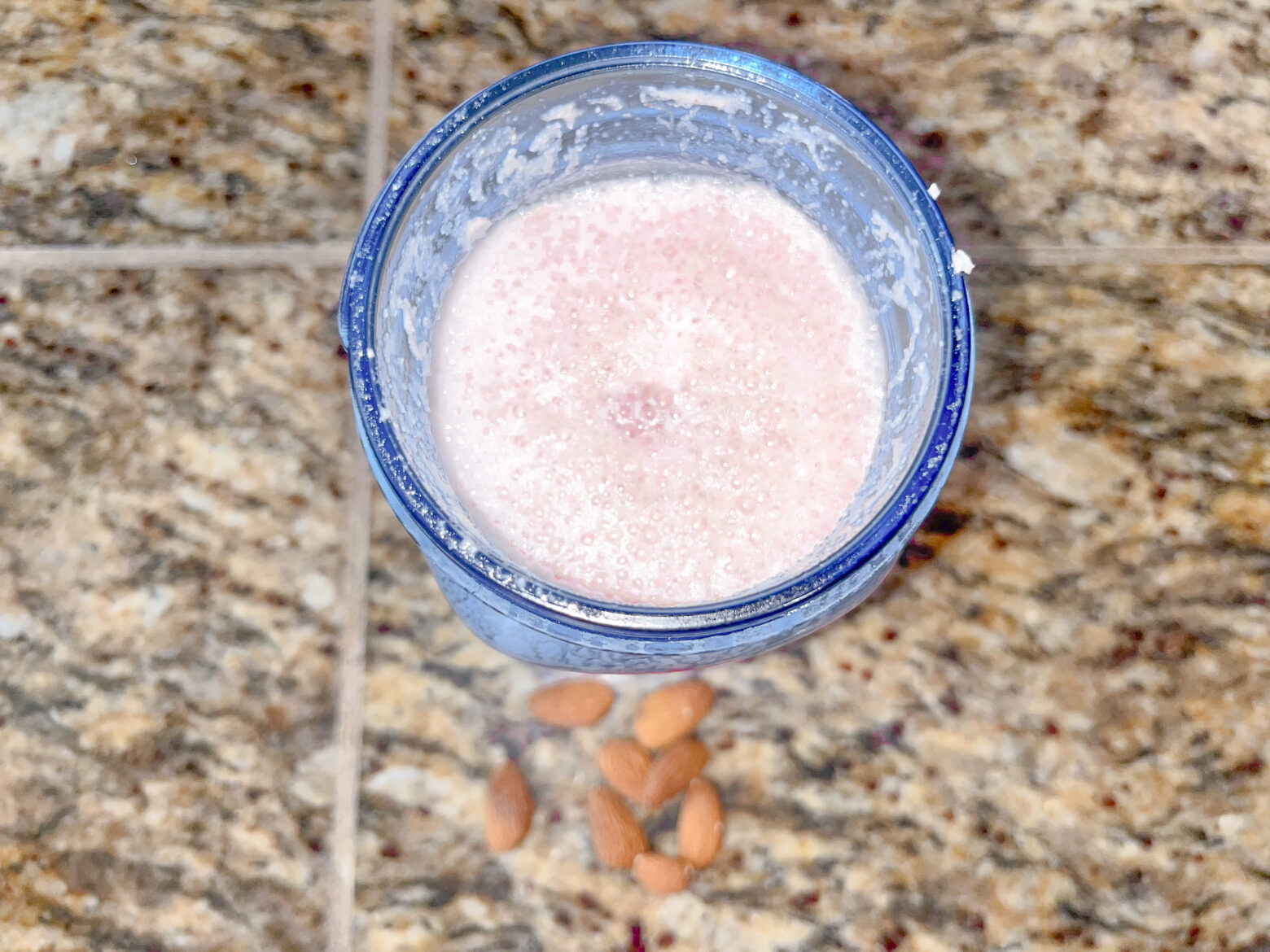 Raspberry almond milk from above on the counter with almonds.