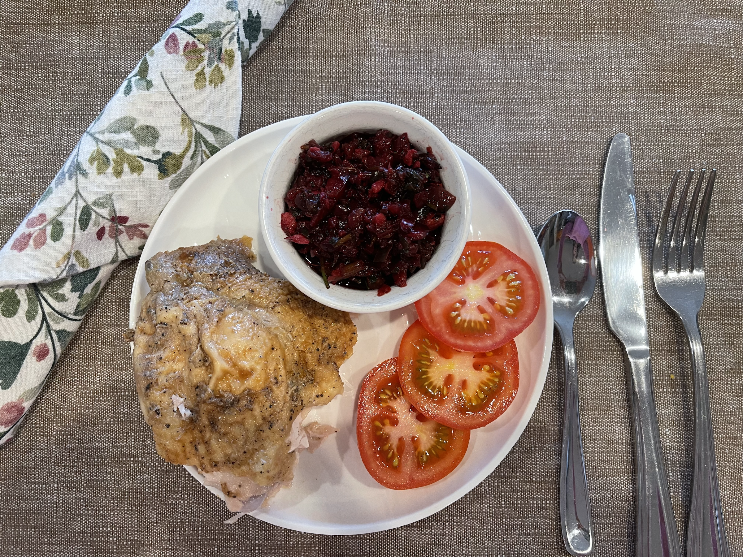 Cherry salsa paired with chicken and tomatoes on a plate. 