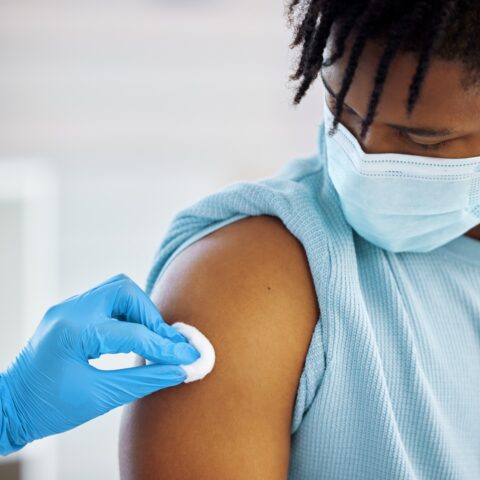 Young man getting his arm swabbed with alcohol to prep for a vaccination