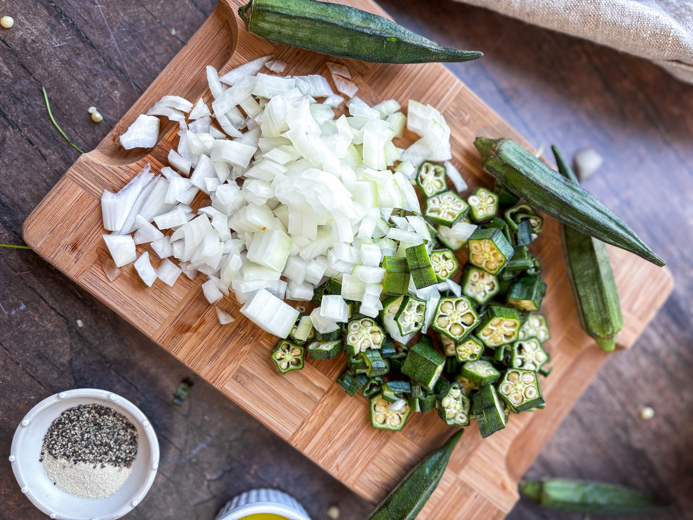 Okra egg bites preparation, onions and okra being chopped on a cutting board. 