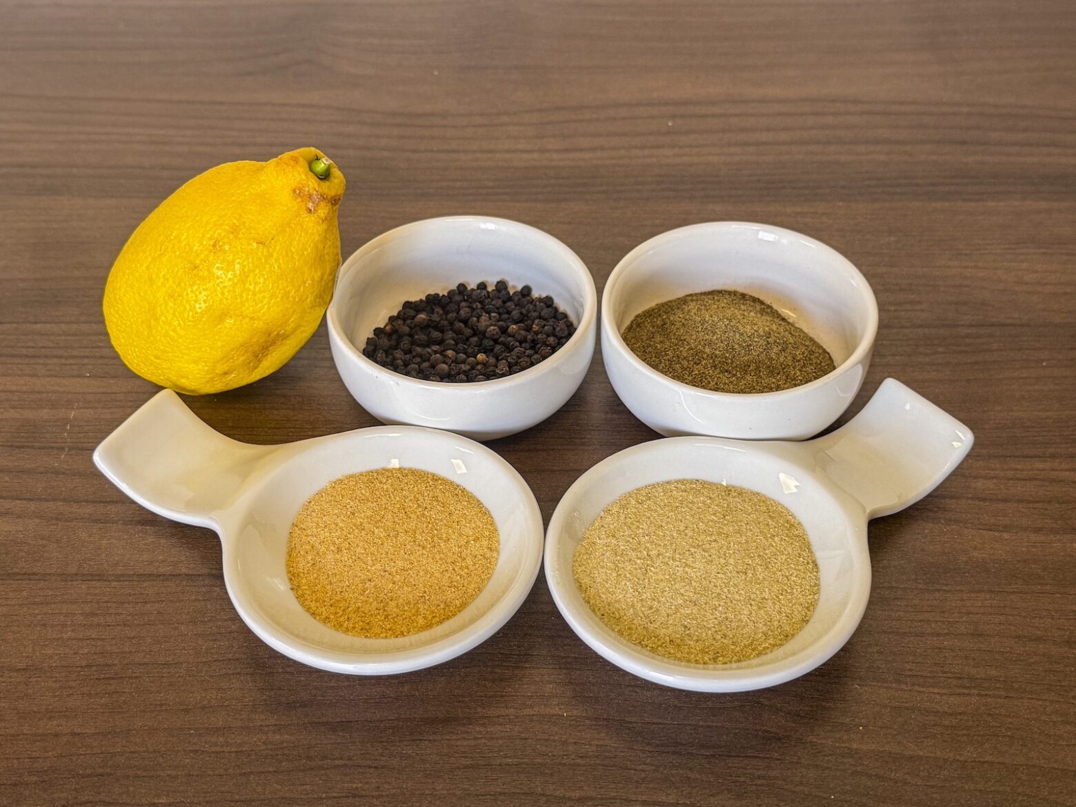 Ingredients photo of whole lemon, ground and whole peppercorns, onion powder, and garlic powder, all in bowls