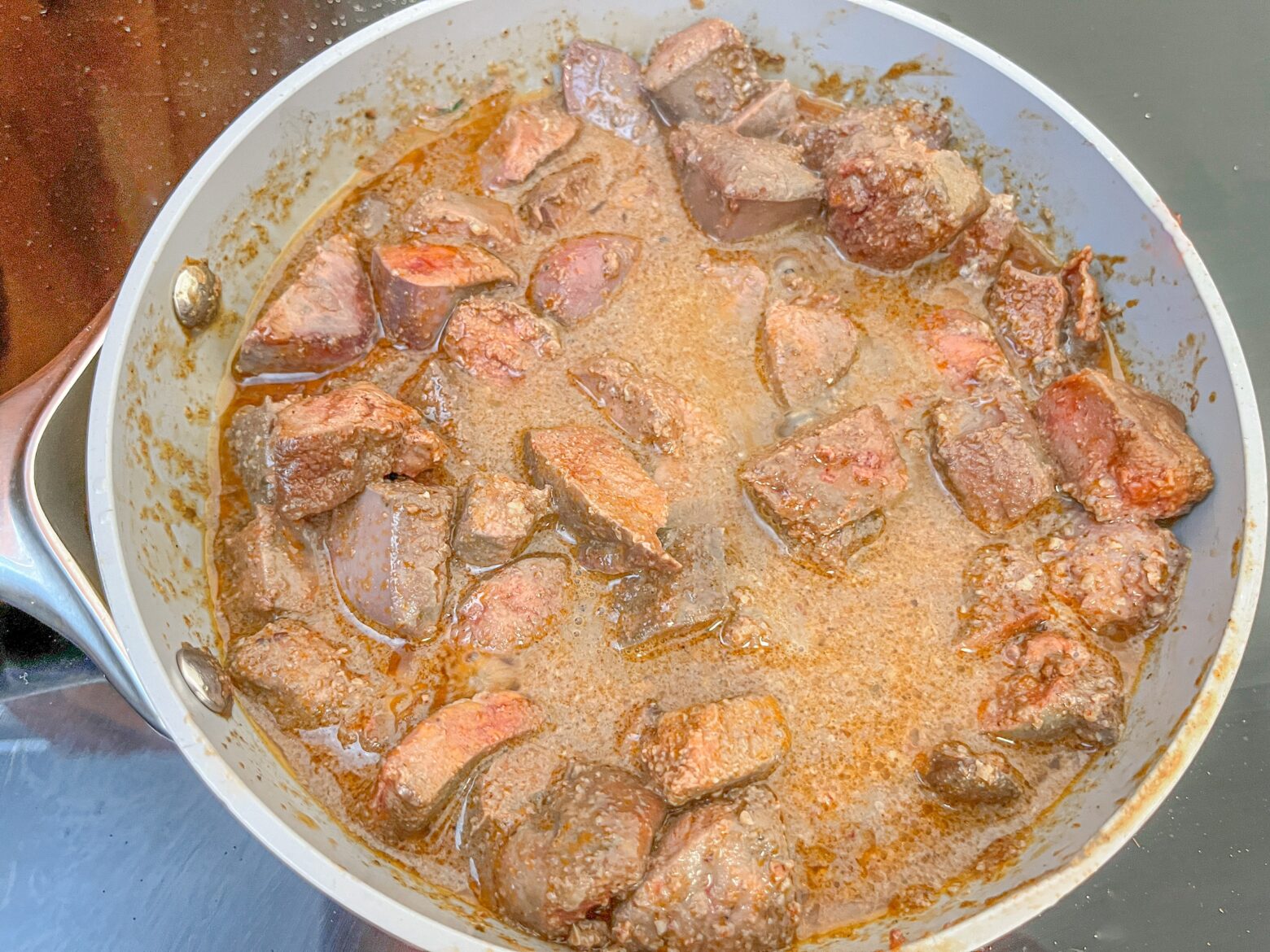 Beef liver chunks in a pan.