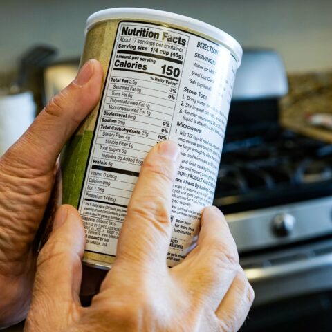 Man examining the nutrition facts label on a container of food.