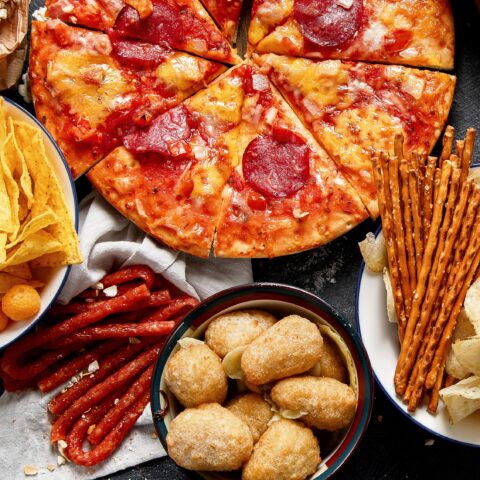Above shot of ultra-processed junk foods that can contribute to metabolic disease, such as pizza, salty snacks, and jerky.