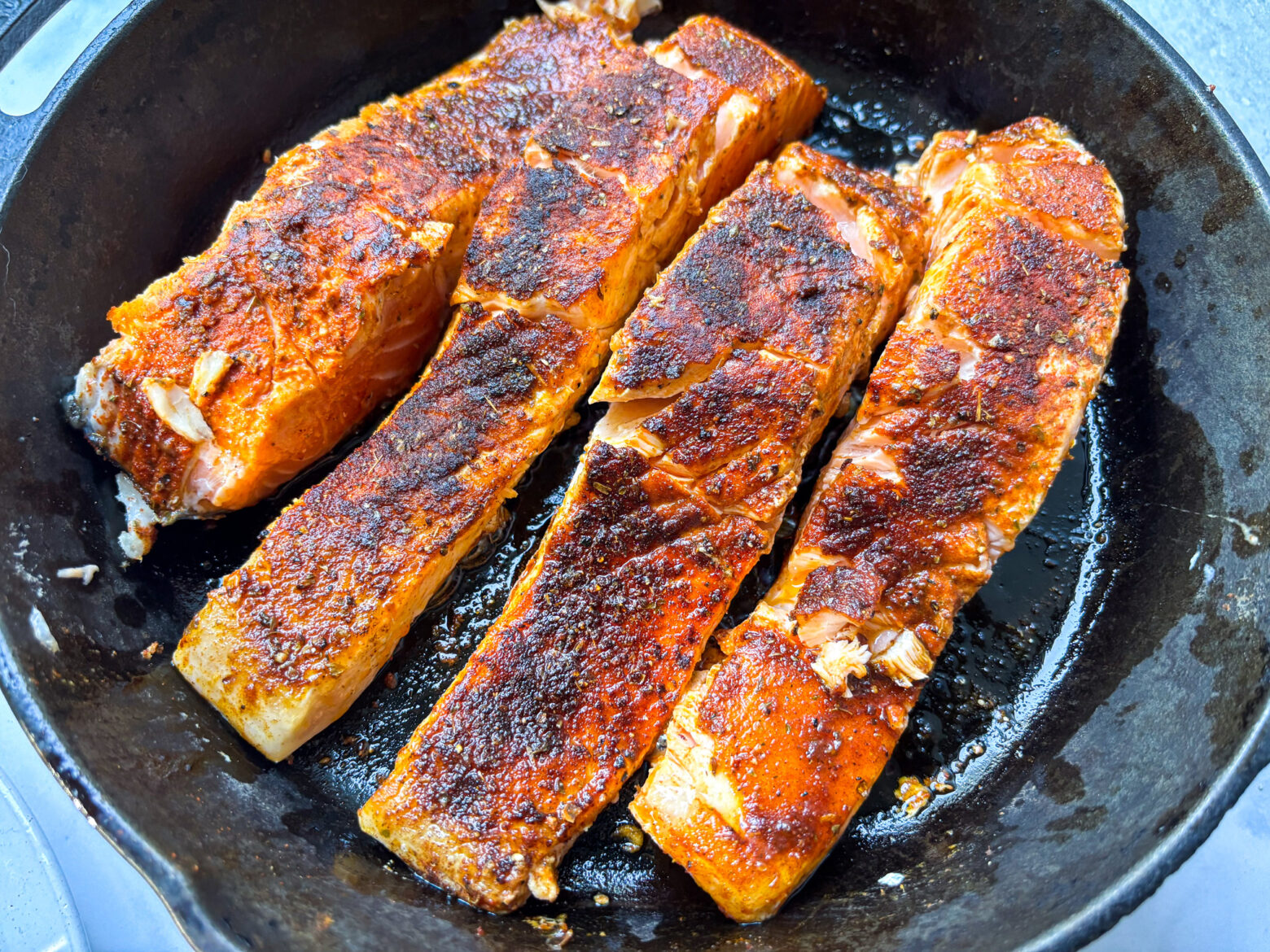 Blackened salmon fillets on a cast iron.