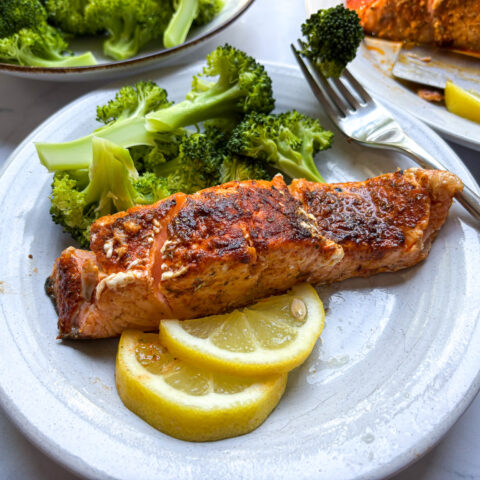 Blackened salmon finished, and plated with lemon slices and broccoli.