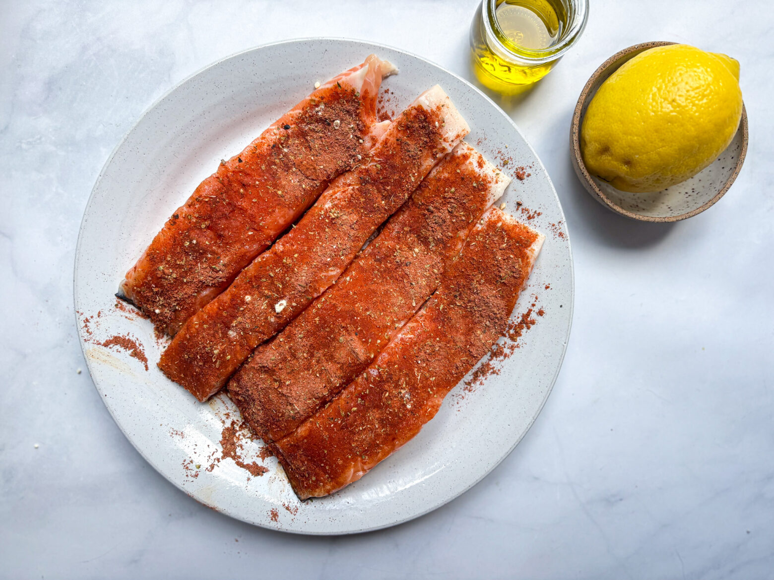 Blackened salmon prep, salmon filets on a white bowl.
