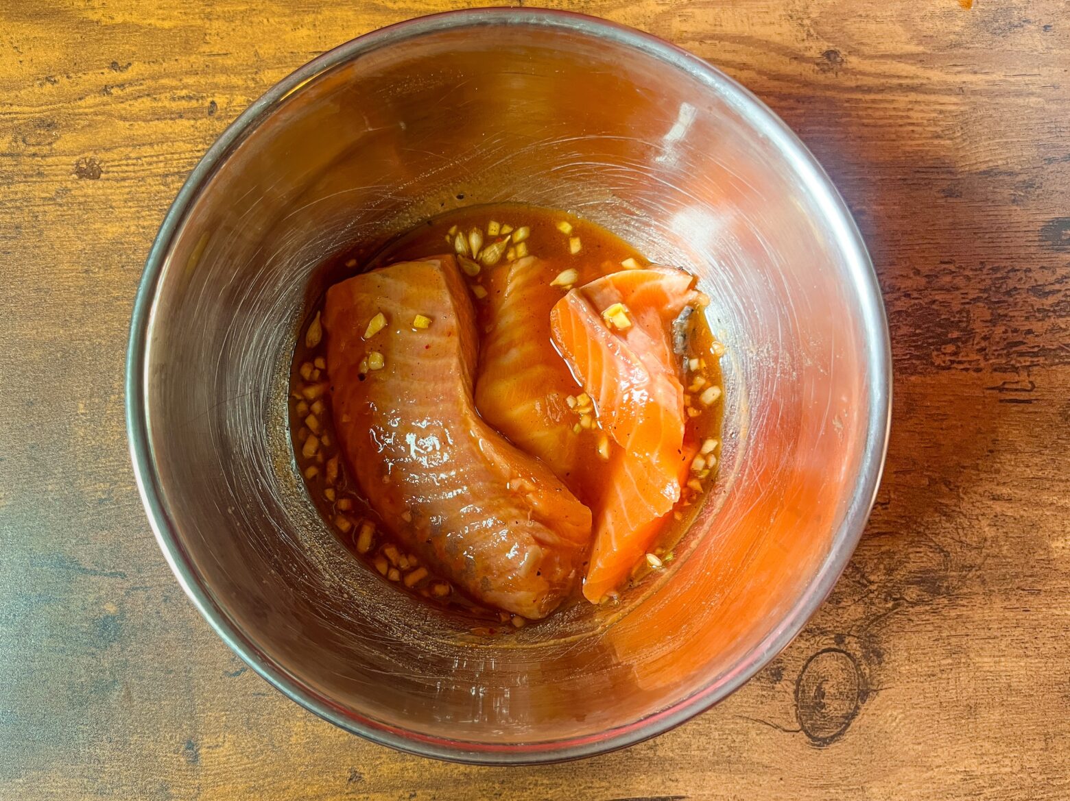 Cedar plank grilled salmon being marinated in a bowl.