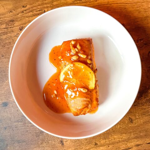 Cedar plank grilled salmon finished with sauce on top.