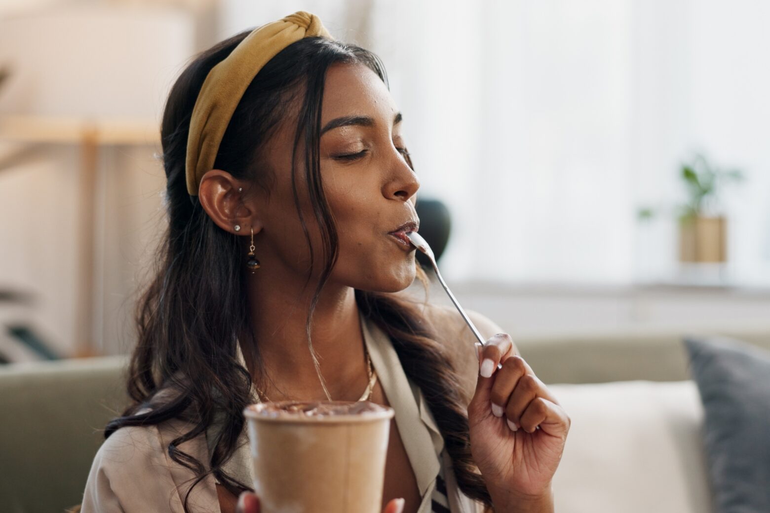 A woman enjoys a spoonful of ice cream from a pint.