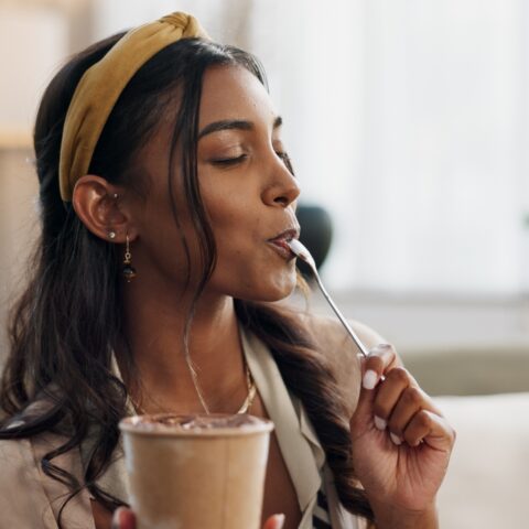 A woman enjoys a spoonful of ice cream from a pint.
