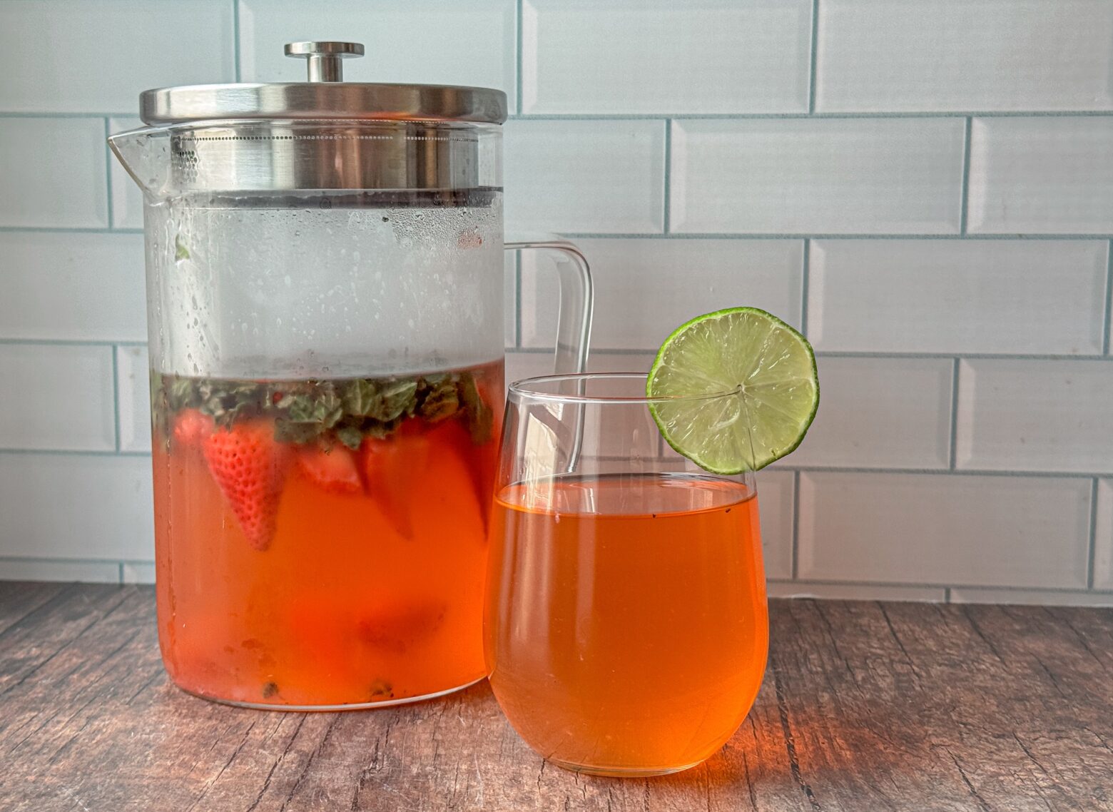Infused water finished in a tall pitcher with a glass next to it.