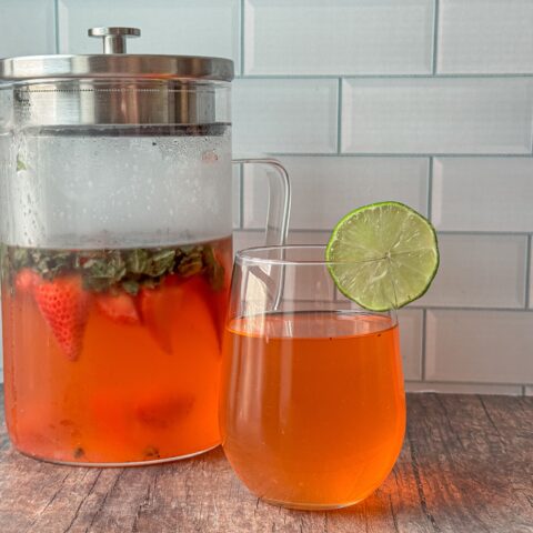 Infused water finished in a tall pitcher with a glass next to it.