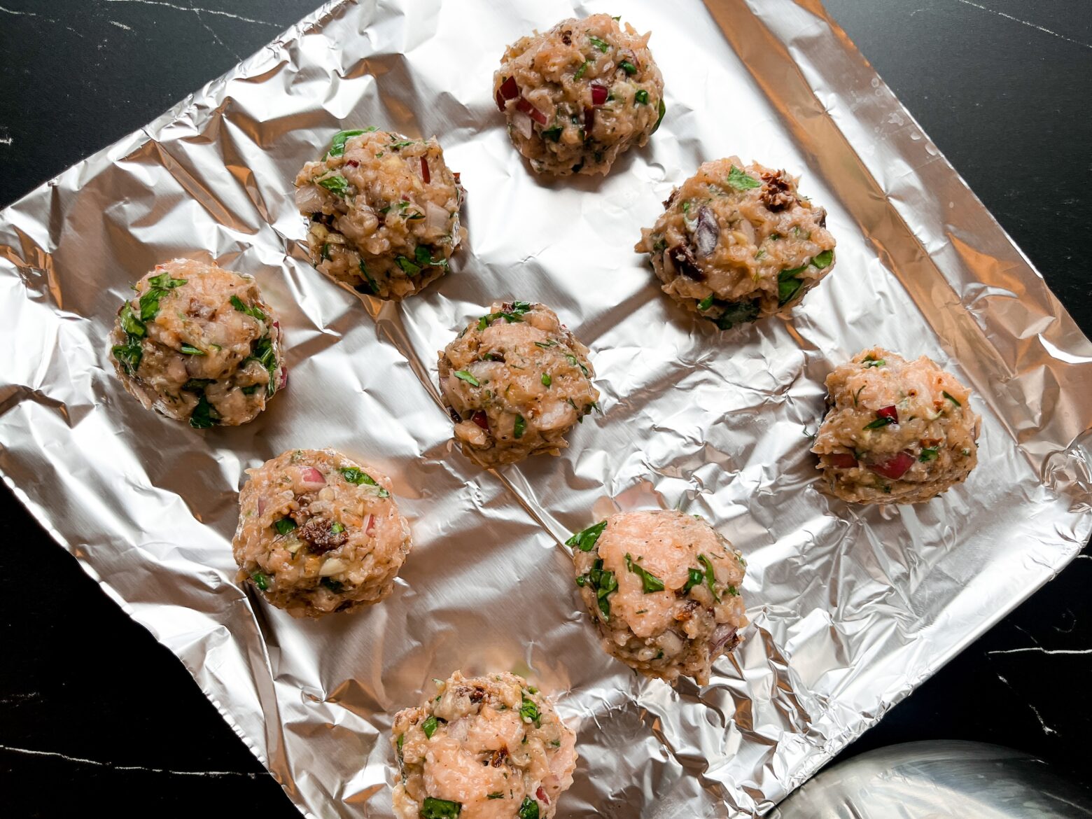 Mediterranean chicken meatballs on a baking tray.