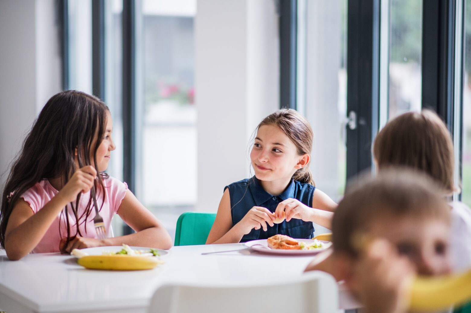 Two young girls enjoying a healthy school lunch.