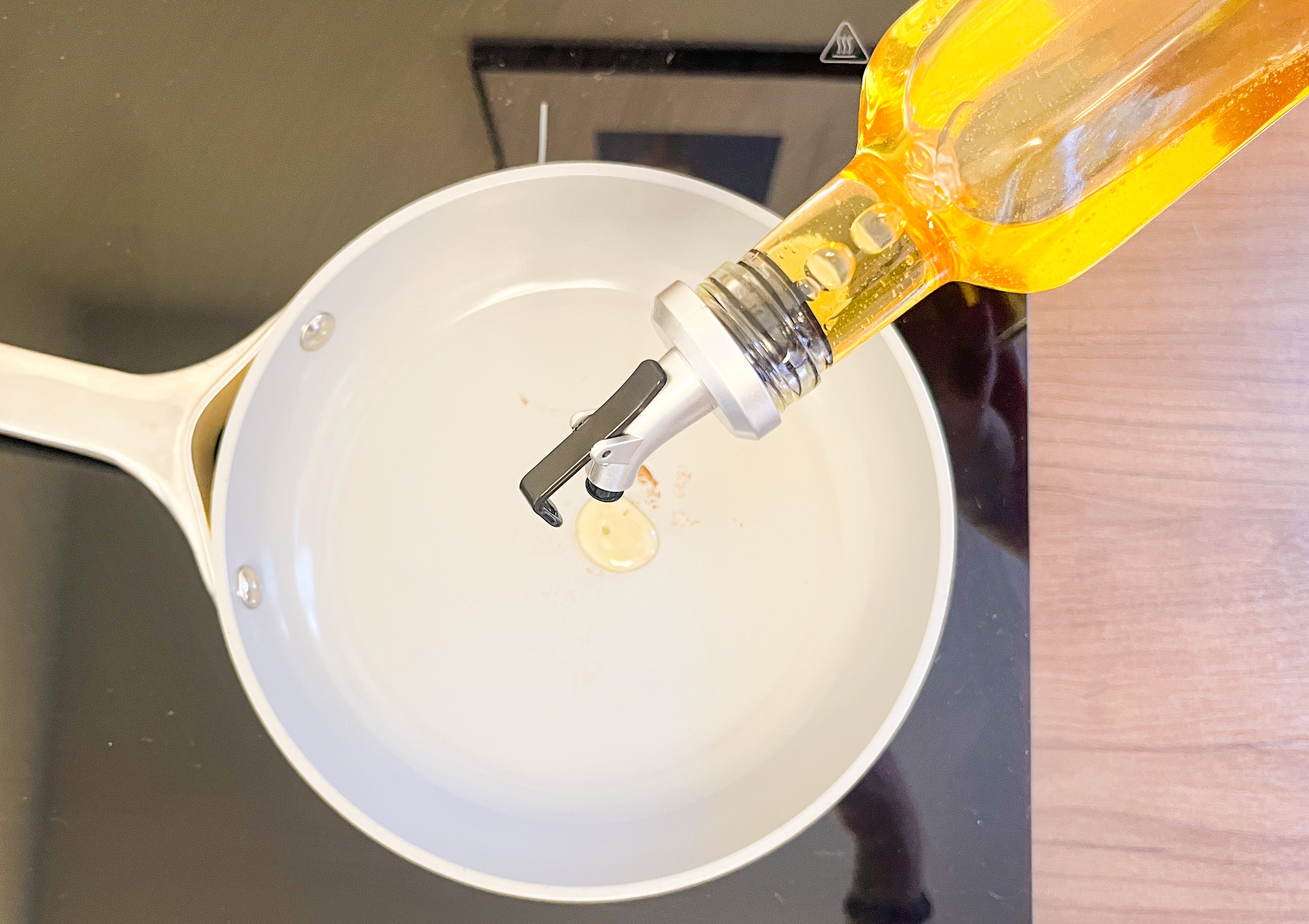 Infused macadamia nut oil being poured out in a pan over the stove. 