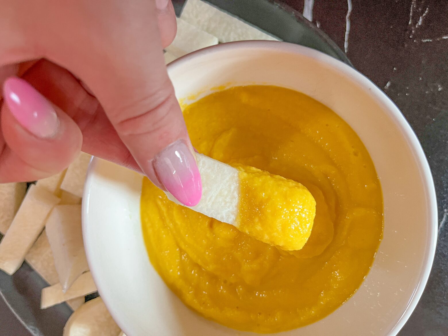 Jicama stick close up in a mango dip.