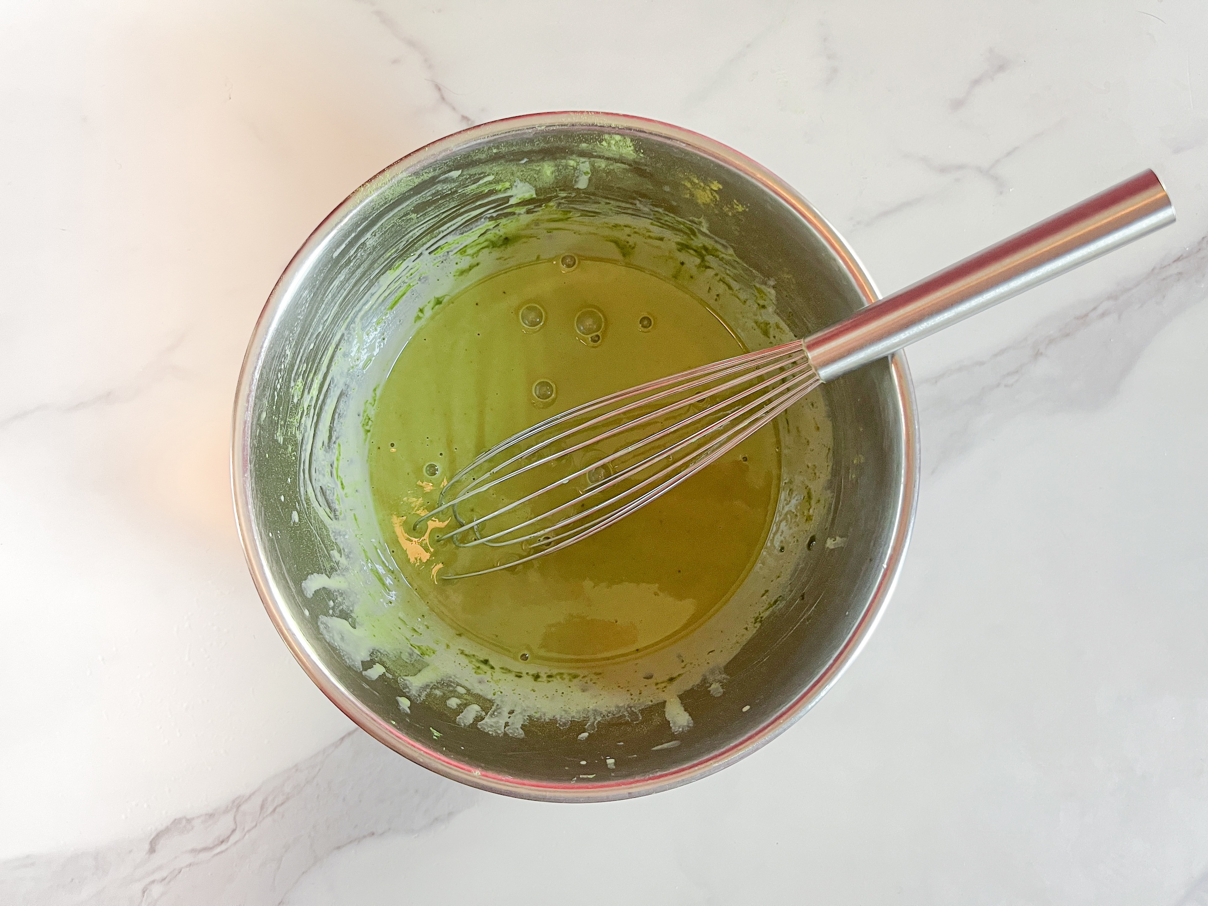 Matcha pudding being stirred in a bowl. 