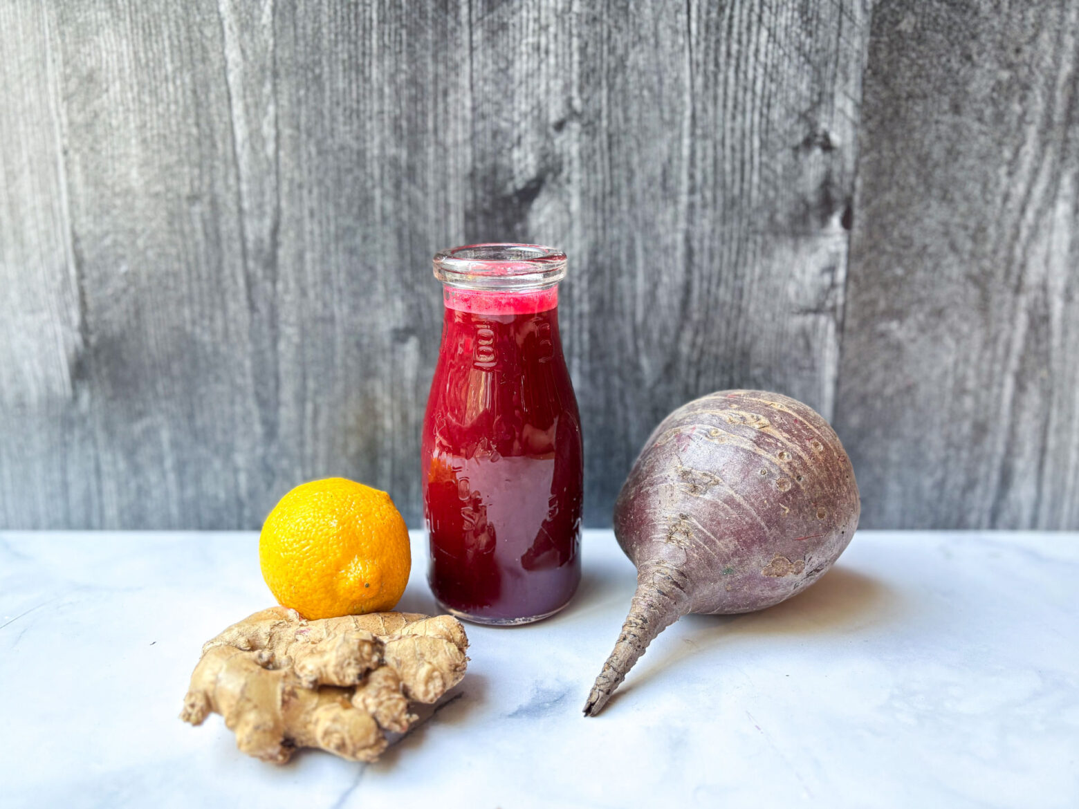 A glass of beet juice with ingredients next to it.