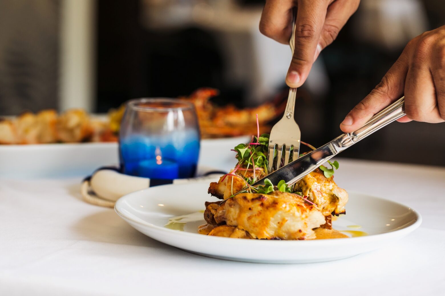 Close up of someone cutting into a fish dinner entree.