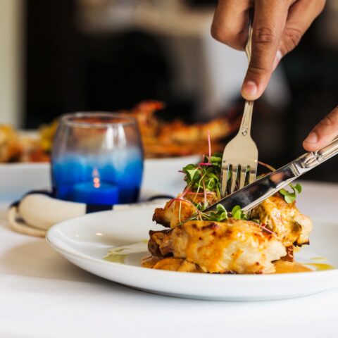 Close up of someone cutting into a fish dinner entree.