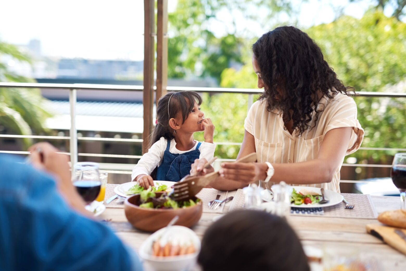A mother and young daughter share a moment while having a healthy lunch outside.