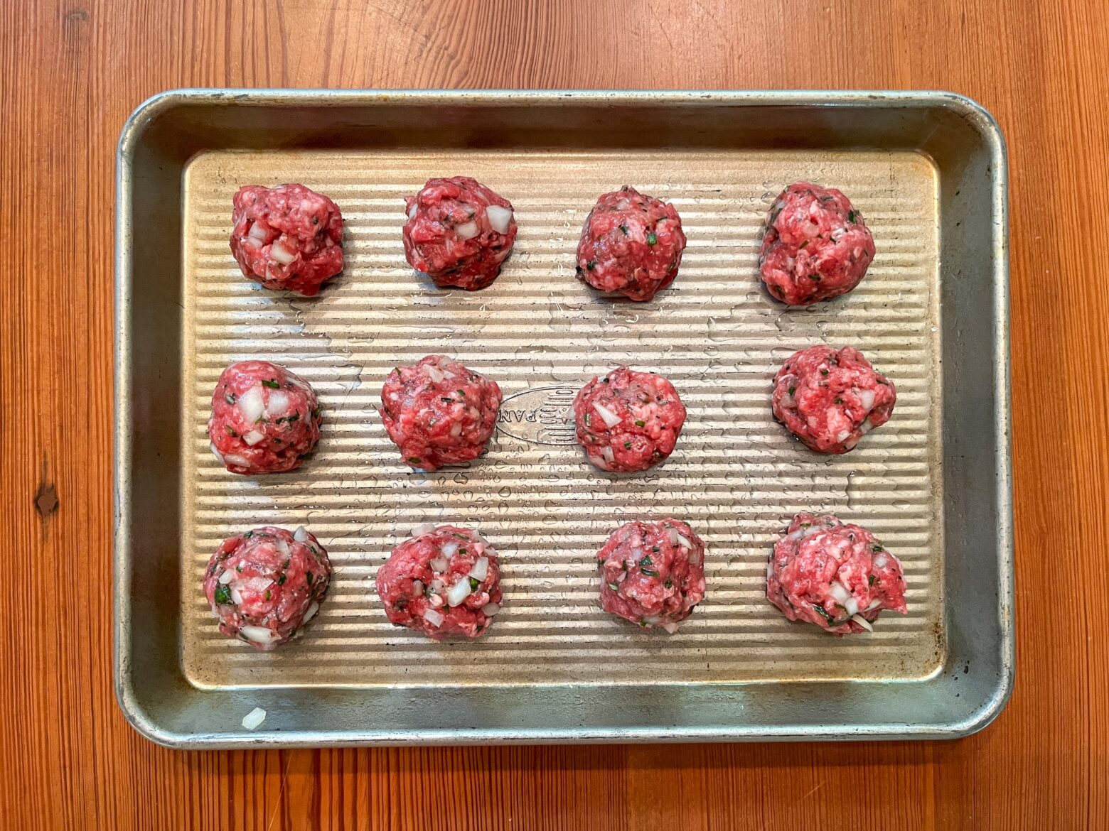 Bison meatballs on a baking sheet.