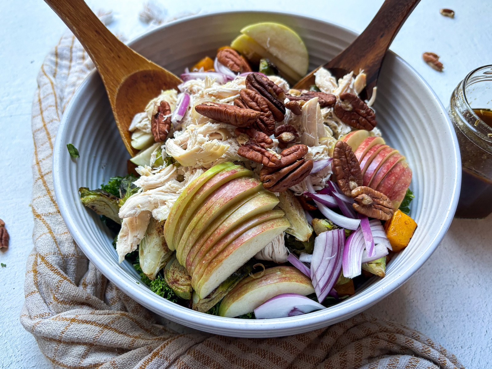 Harvest protein bowl in a large bowl being mixed with two wooden spoons. 