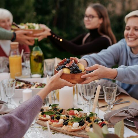 A family passes plates while enjoying dinner outside.