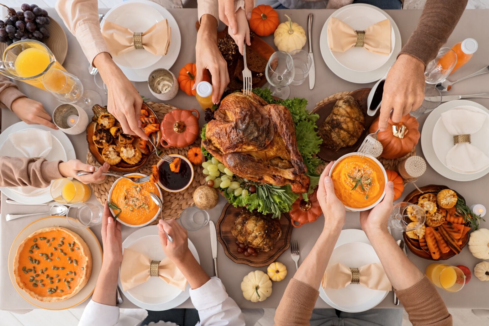 Above shot of a family plating a holiday dinner with a roasted turkey as the main dish.