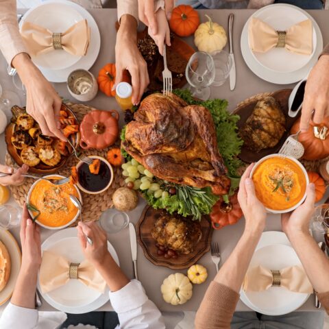 Above shot of a family plating a holiday dinner with a roasted turkey as the main dish.