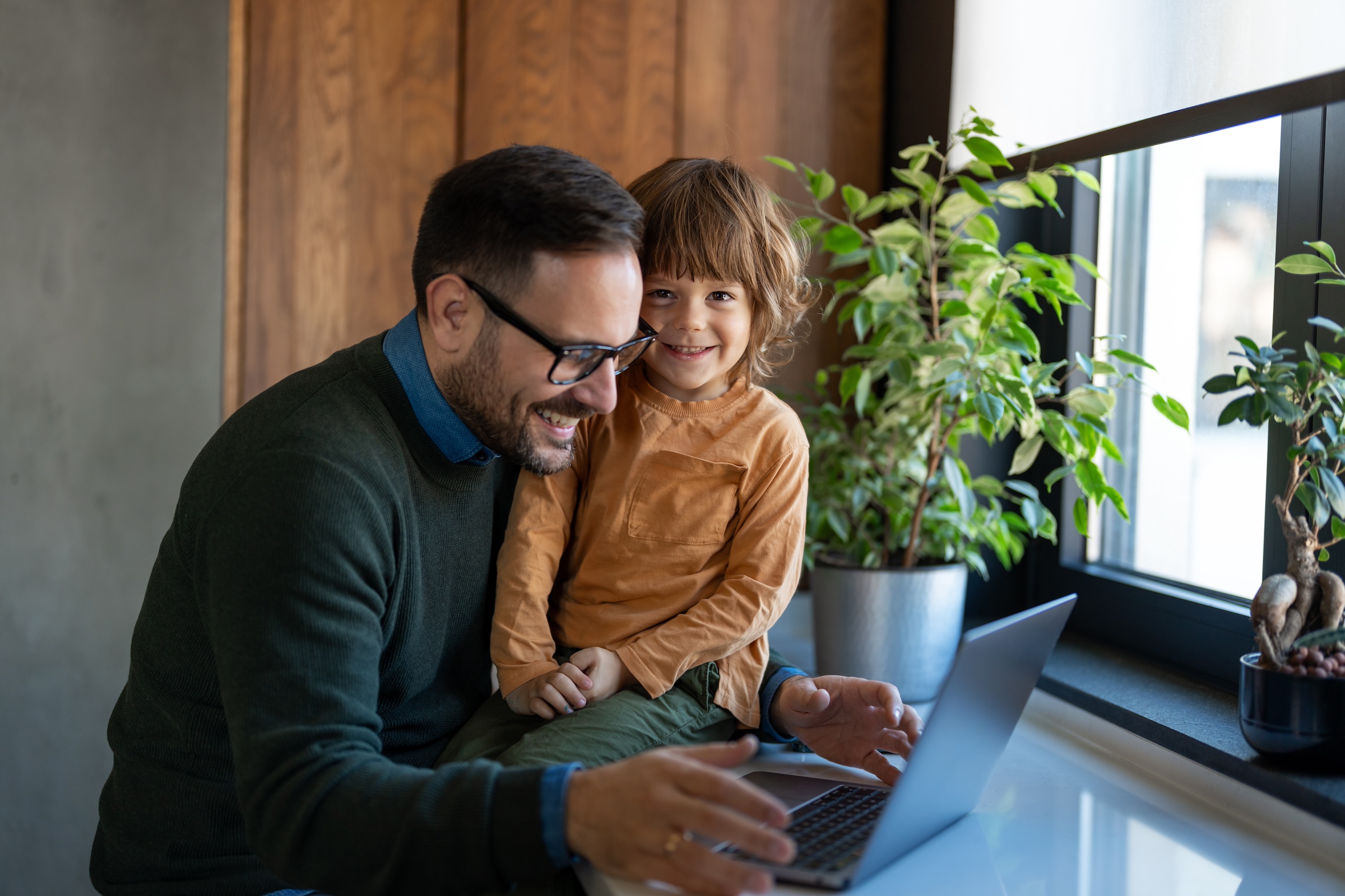 Dad with son on laptop looking happy.