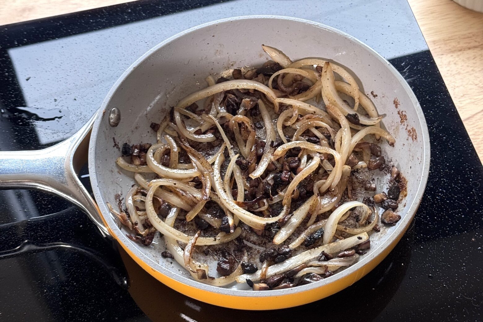 Cooked onions and mushrooms in a pan.