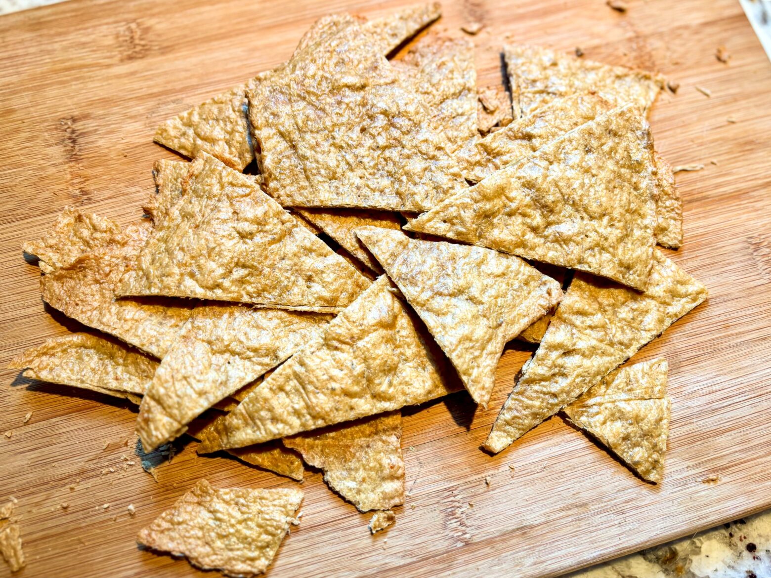 Chicken chips broken into pieces on a cutting board.