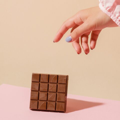 A hand reaching from out of shot for a chocolate bar.