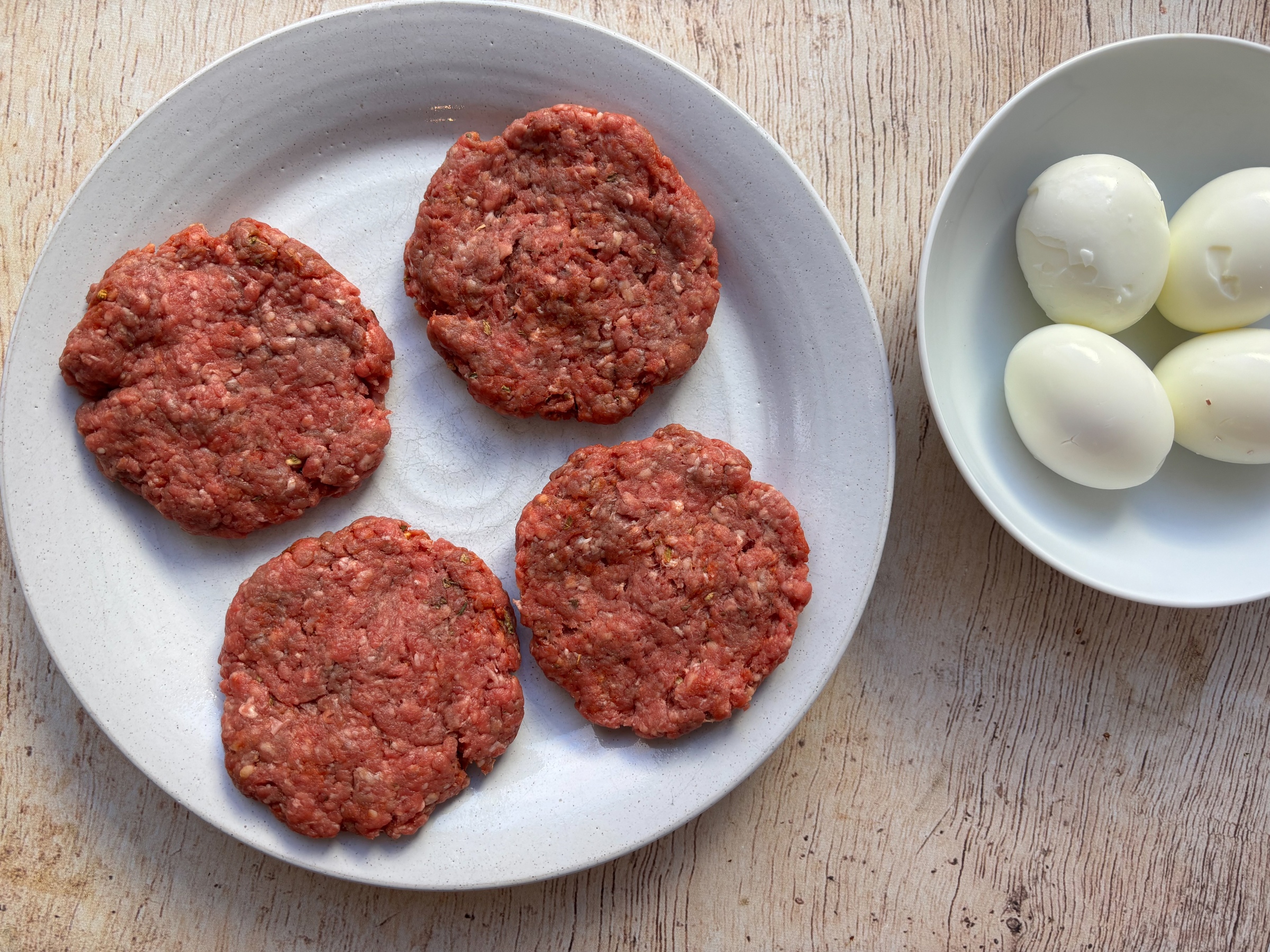 Pork patties and hardboiled eggs ready to assemble into Scotch eggs
