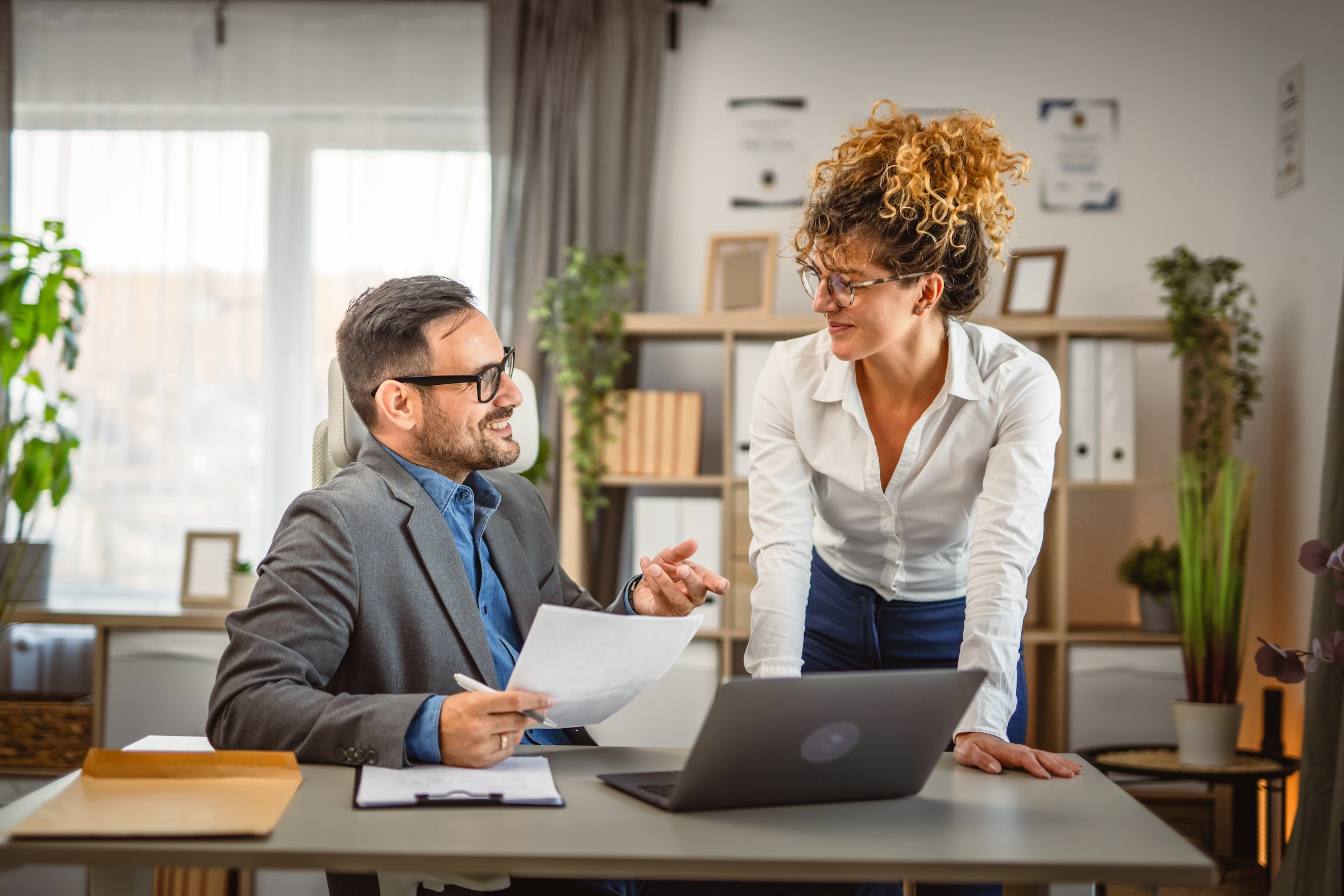 Women and a man talking at the office over the desk.