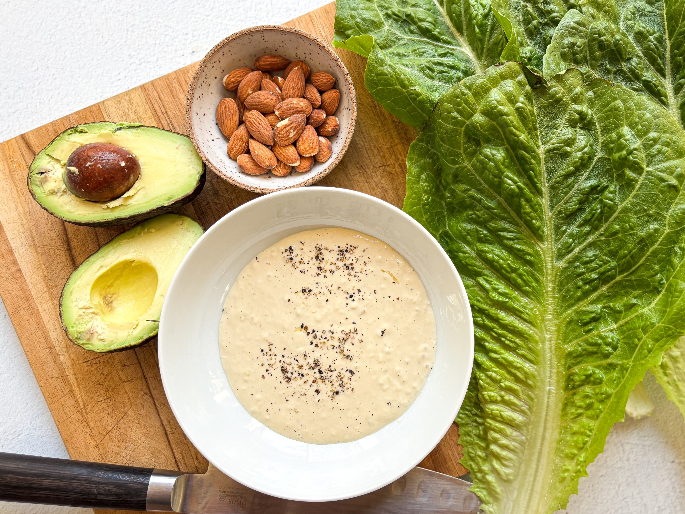 Fresh Caesar Salad dressing next to other salad ingredients.