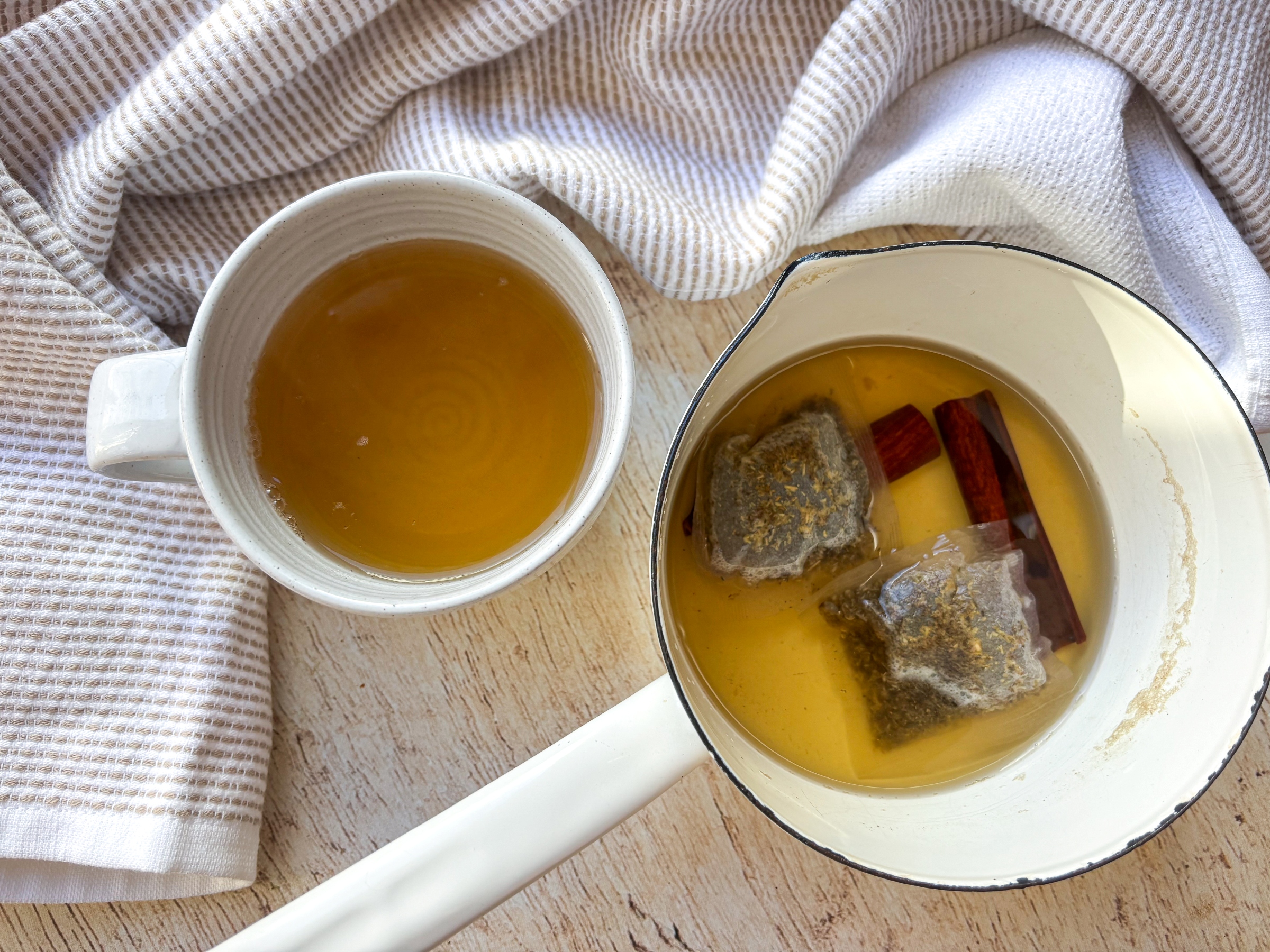 Steeped Chamomile Cinnamon Tea in a pot next to a cup of tea.